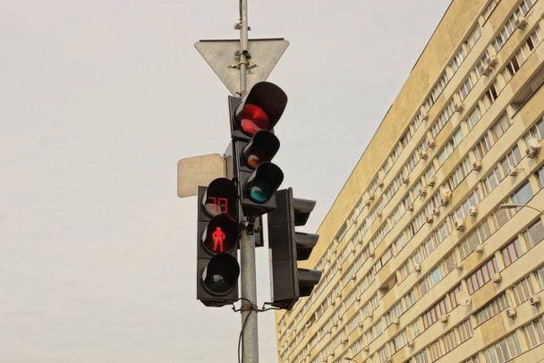 semáforos em um pólo na rua contra o céu e a parede da casa
 - Foto, Imagem