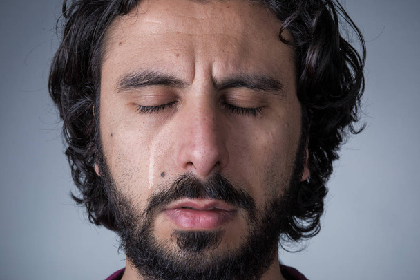 Homme aux cheveux longs et barbus pleurant avec les yeux fermés
 - Photo, image
