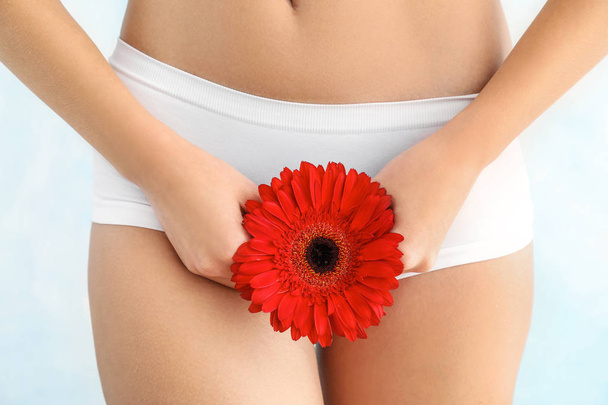 Beautiful young woman in underwear and with flower on light background - Foto, Bild