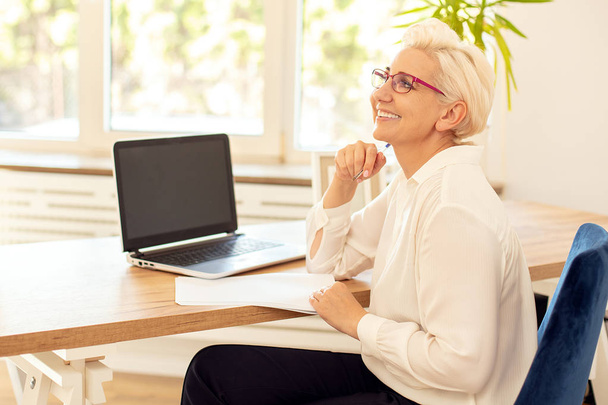 Happy businesswoman sitting at desk in office. - Photo, image