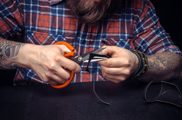 Man werkt met leer snijden lederen contouren voor zijn nieuwe productie in zijn studio - Foto, afbeelding