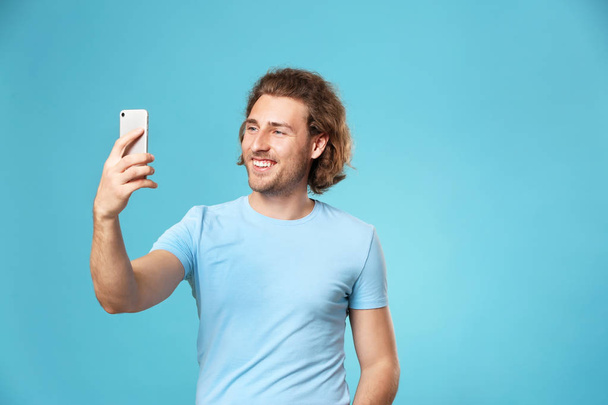 Handsome happy man taking selfie on color background - Foto, Bild