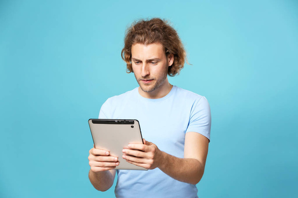 Handsome man with tablet computer on color background - Фото, изображение
