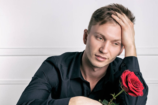 Handsome man wearing black shirt holding a rose and getting ready romantic date - Photo, Image