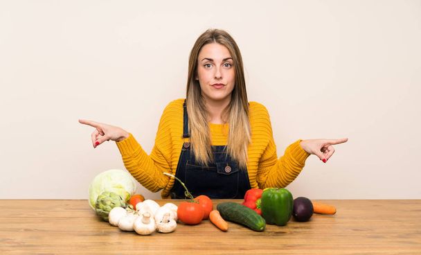 Vrouw met veel groenten wijst naar de lateralen met twijfels - Foto, afbeelding