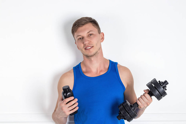 Handsome young man in blue shirt lifting dumbbell. White background - Foto, Imagem