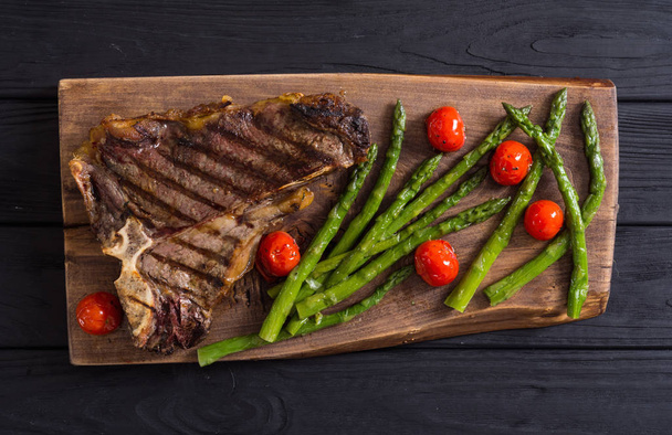 Grilled T-bone steak with asparagus and cherry tomatoes  - Фото, зображення