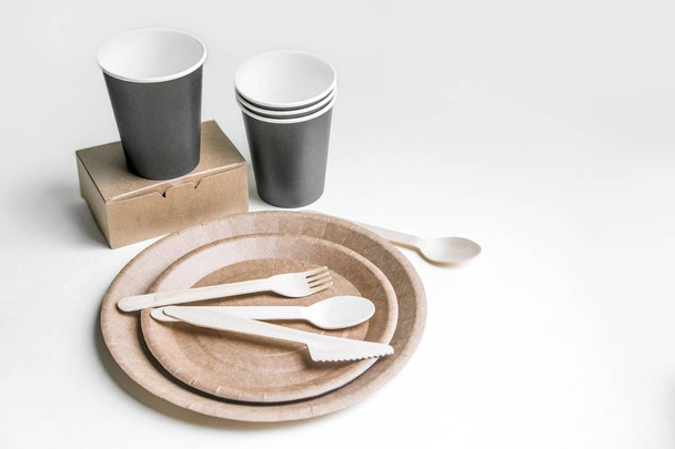 eco friendly disposable dishes made paper on white marble background. Draped spoons, fork, knives, plate with paper cups. recycling concept - Photo, Image