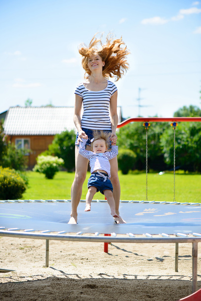 Young mother and little daughter bouncing on trampoline - Foto, afbeelding