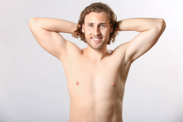 Γυμνός νέος άνθρωπος μετά την αποτρίχωση σε ανοιχτόχρωμο φόντο - Φωτογραφία, εικόνα