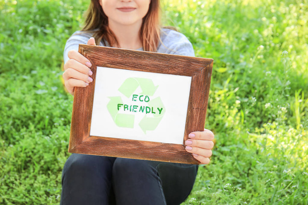 Young woman holding board with text ECO FRIENDLY outdoors - Photo, Image