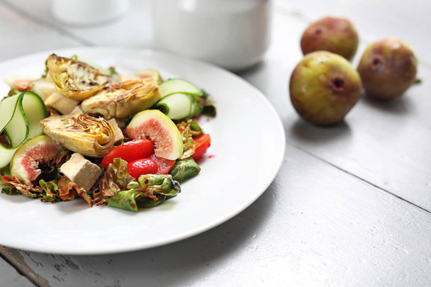 exquisiter Salat mit Feigen, Artischocken, Gurken, Tomaten, Feta auf Lammsalatblättern mit Himbeersoße. - Foto, Bild