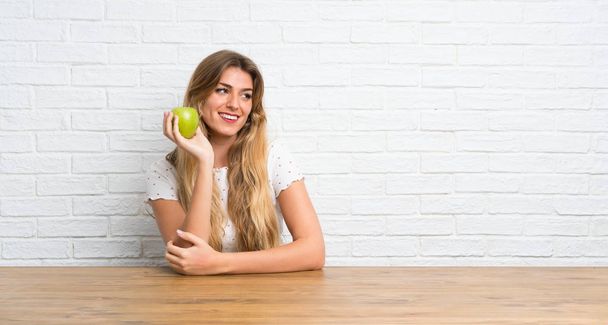 Gelukkige jonge blonde vrouw met een appel - Foto, afbeelding
