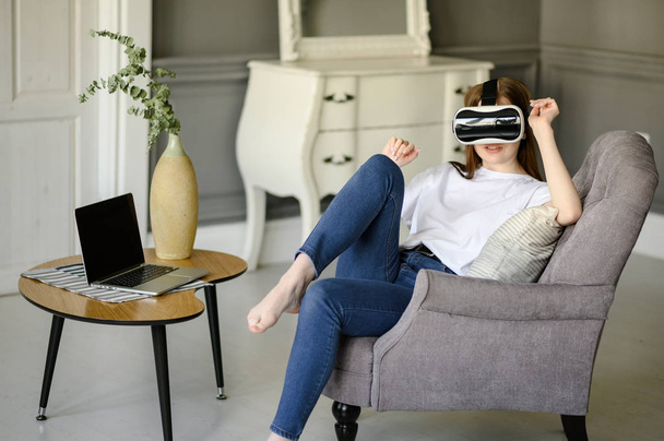 Молодая женщина регулирует свой VR гарнитуру и улыбается, находясь дома
 - Фото, изображение