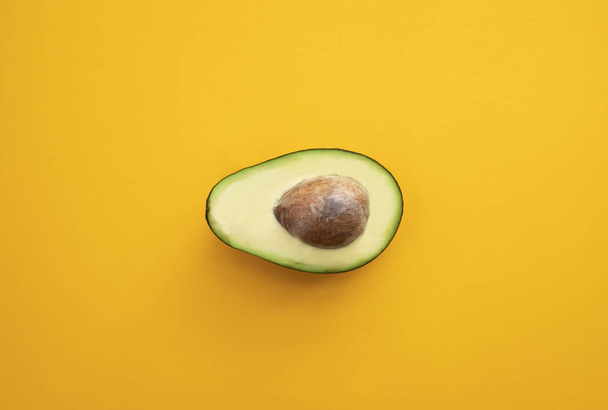 Close up ripe sliced avocado on bright yellow background top vie - Foto, afbeelding