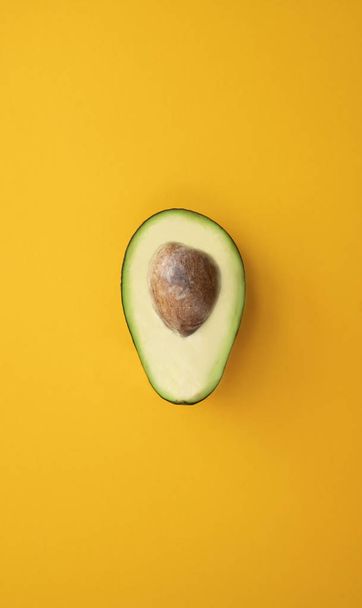 Закрыть спелый нарезанный авокадо на ярко-желтом фоне
 - Фото, изображение