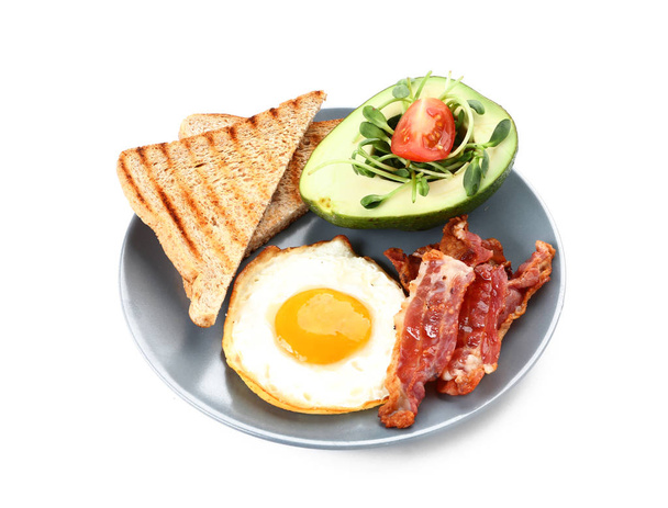 Plate with tasty fried egg, bacon, avocado and toasts on white background - Photo, Image
