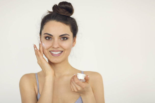 junge Frau trägt Gesichtscreme auf perfekte Haut auf - Foto, Bild