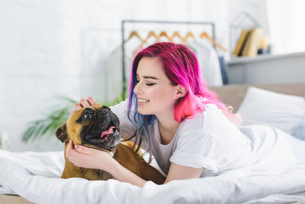 girl with colorful hair laying in bed with french bulldog  - Fotografie, Obrázek