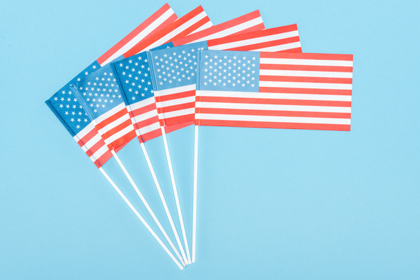 top view of american flags on sticks on blue background - Foto, afbeelding