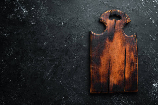 Old Wooden kitchen board on a black background. Top view. Free space for your text. - Zdjęcie, obraz