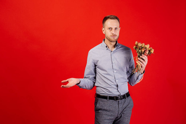 man is holding a bouquet of dead and withered flowers - Foto, Bild