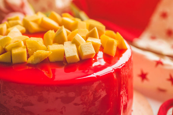 Verjaardagstaart met een kaars en rode glazuur. Nationale bakkerij. Ronde taart met mango - Foto, afbeelding