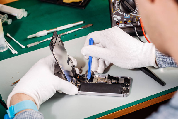 Close up hands of a service worker repairing modern smarphone. Repairing and service concept. - Фото, зображення
