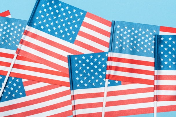 Close-up weergave van decoratieve Amerikaanse vlaggen op stokken op blauwe achtergrond - Foto, afbeelding
