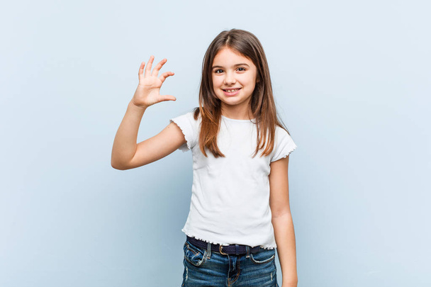 Cute girl holding something little with forefingers, smiling and confident. - Foto, afbeelding