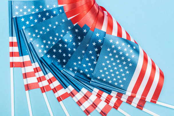 close up vista de bandeiras americanas de seda em paus no fundo azul
 - Foto, Imagem