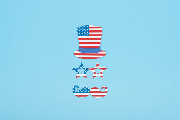 platte lay met papier gesneden snor, glazen en hoed gemaakt van USA vlaggen op blauwe achtergrond - Foto, afbeelding