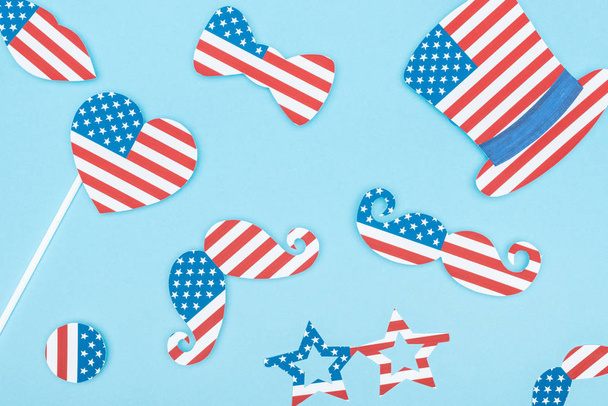 top view of paper cut decorative mustache, glasses, hat and heart made of usa flags on blue background  - Foto, Imagen