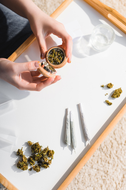 top view of girl closing herb grinder with medical cannabis in sunlight  - Fotografie, Obrázek