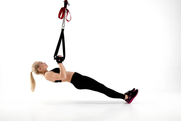 The girl does pull-ups using special equipment. - Foto, imagen