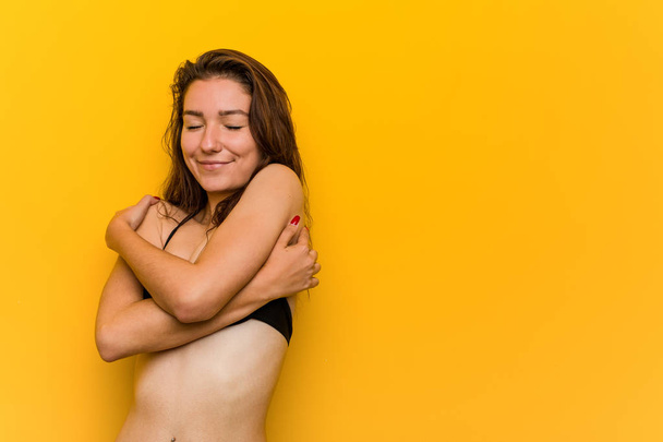 Joven mujer europea con bikini se abraza, sonriendo despreocupada y feliz
. - Foto, imagen