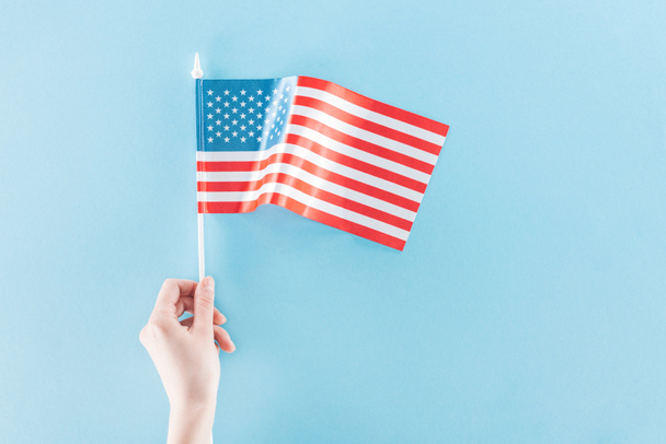 vista parcial de la mujer sosteniendo bandera nacional americana sobre palo sobre fondo azul
 - Foto, imagen