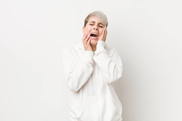 Μια νεαρή γυναίκα με λευκή κουκούλα να κλαψουρίζει και να κλαίει απαρηγόρητη.. - Φωτογραφία, εικόνα