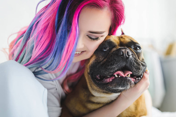 cheerful girl with colorful hair hugging cute bulldog - Foto, imagen