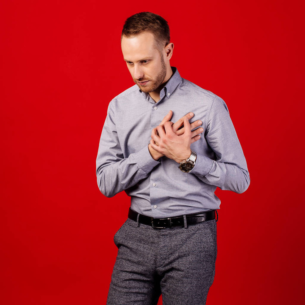man suffering from heartache over red background. people and healthcare concept - Valokuva, kuva