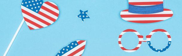panoramic shot of paper cut decorative glasses, hat, lips, star and heart made of usa flags on blue background  - Valokuva, kuva