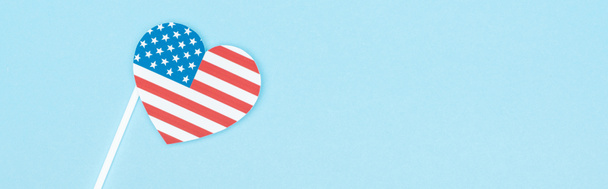 top view of paper cut decorative heart on stick made of american flag on blue background, panoramic shot - 写真・画像