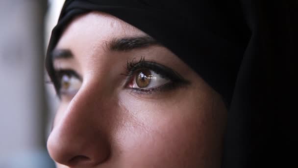 Ακραία κοντά σε μια νέα Μέση Ανατολή μουσουλμανική γυναίκα με μαύρη μαντίλα ανοίγοντας σκούρα καστανά μάτια και κοιτάζοντας προς τα εμπρός. Αναβοσβήνει σε αργή κίνηση - Πλάνα, βίντεο
