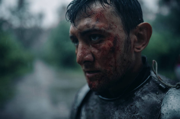 Retrato de um jovem à imagem de um cavaleiro medieval com sangue e feridas no rosto
. - Foto, Imagem