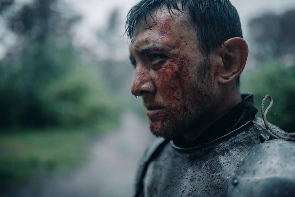 Yüzünde kan ve yaralar olan bir ortaçağ şövalyesi görüntüsünde genç adamın portresi. - Fotoğraf, Görsel