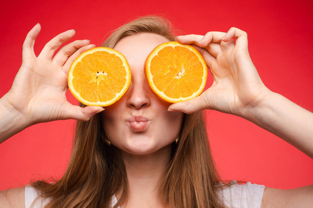 Χαρούμενη νεαρή ξανθιά ποζάρει με φρέσκα πορτοκάλια - Φωτογραφία, εικόνα