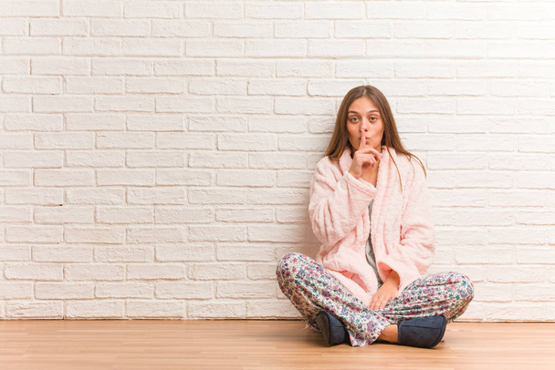 Jonge vrouw in pyjama die een geheim bewaart of om stilte vraagt - Foto, afbeelding