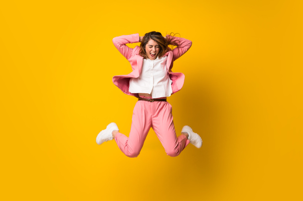 junge Frau springt über isolierte gelbe Mauer - Foto, Bild