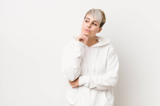 Young curvy woman wearing a white hoodie looking sideways with doubtful and skeptical expression. - Foto, afbeelding
