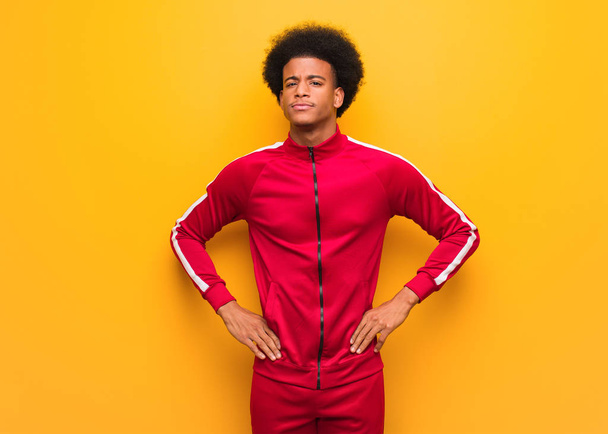 Young sport black man over an orange wall with hands on hips - 写真・画像